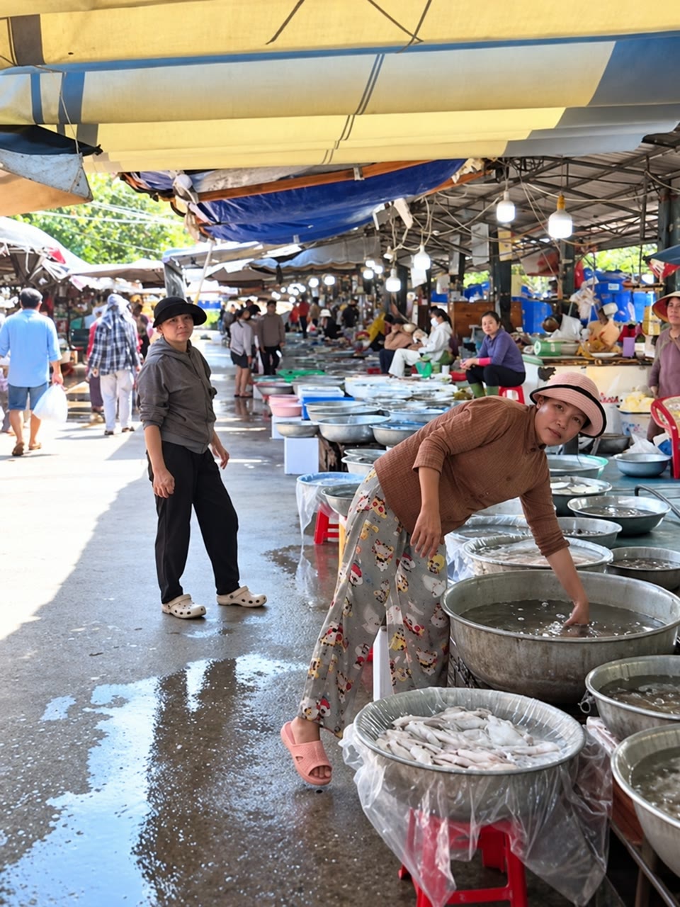 Người bán bên các thau hải sản và mực tại chợ Hồ Tràm