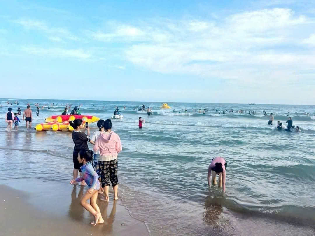 Du khách và các gia đình vui chơi gần bờ tại bãi tắm Hồ Tràm